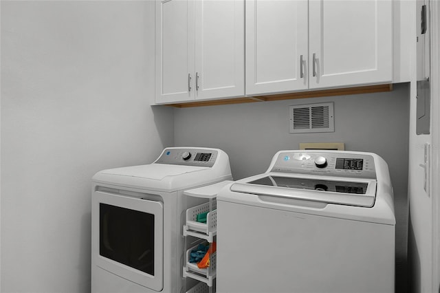 clothes washing area with cabinet space, visible vents, and separate washer and dryer