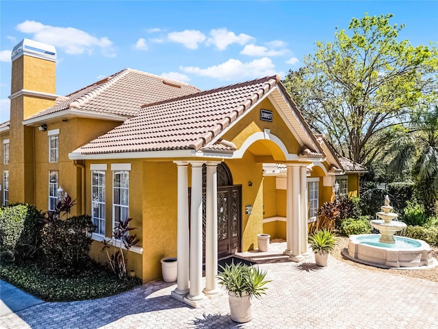 exterior space with a chimney, a tiled roof, and stucco siding