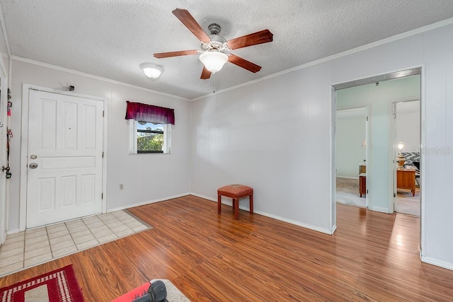 entrance foyer with a textured ceiling, wood finished floors, a ceiling fan, and ornamental molding