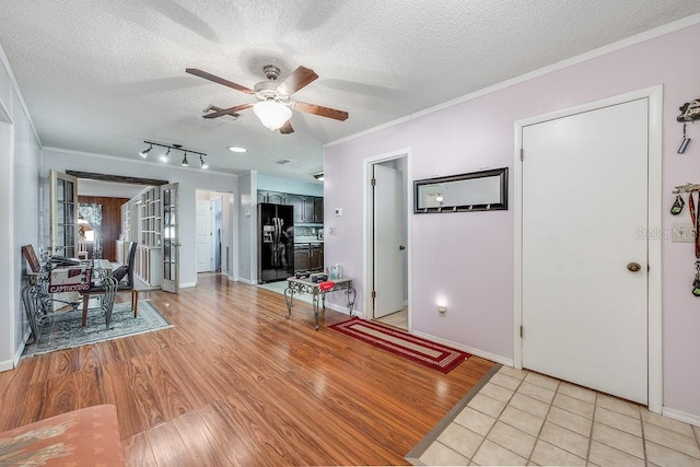 entryway with light wood-type flooring, a textured ceiling, crown molding, and a ceiling fan