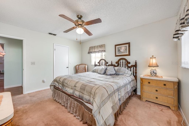 bedroom with visible vents, light carpet, a textured ceiling, and baseboards