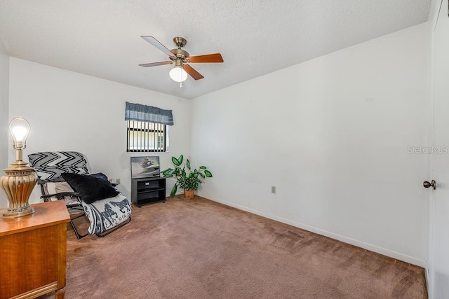 sitting room featuring a textured ceiling, baseboards, carpet floors, and ceiling fan