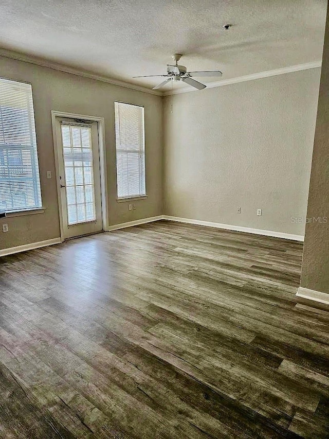 spare room featuring baseboards, ceiling fan, ornamental molding, dark wood-style flooring, and a textured ceiling