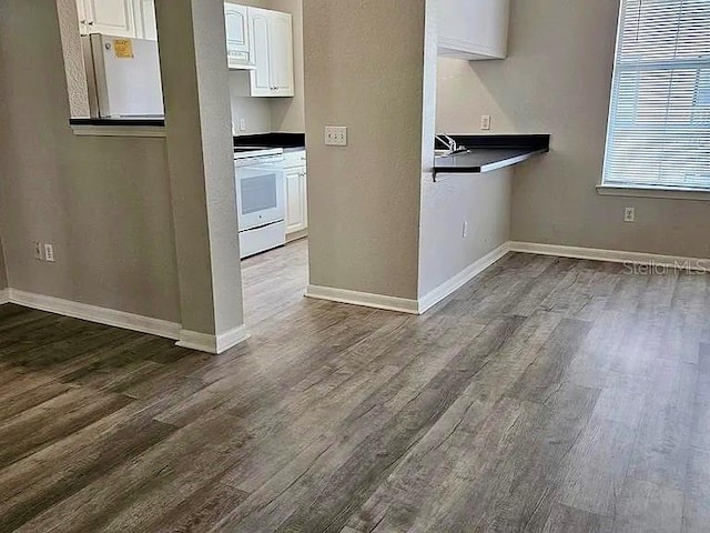 kitchen featuring baseboards, white cabinets, freestanding refrigerator, range, and dark wood-style floors