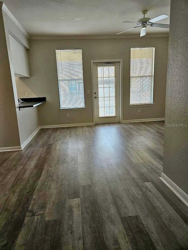 interior space with ceiling fan, a textured ceiling, baseboards, and wood finished floors