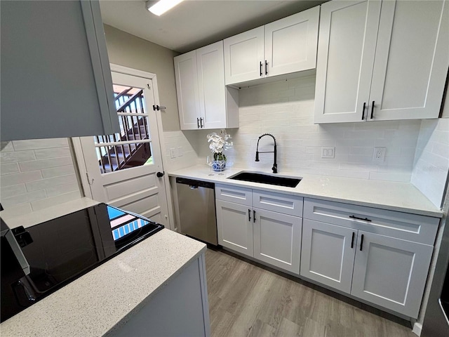 kitchen with backsplash, dishwasher, light wood-style flooring, and a sink