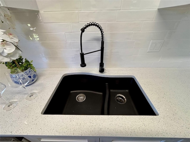 details featuring a sink, decorative backsplash, and light stone countertops