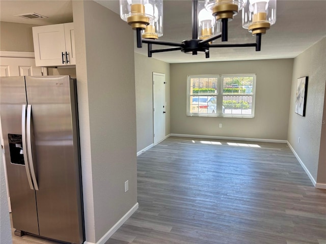 kitchen with stainless steel fridge, visible vents, baseboards, an inviting chandelier, and white cabinetry