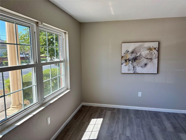 unfurnished room with baseboards and dark wood finished floors