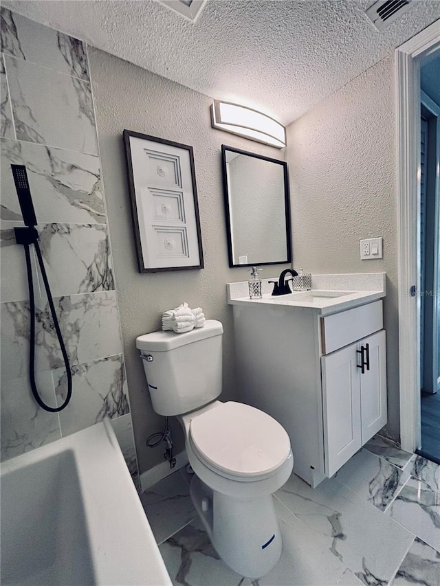 full bathroom with toilet, marble finish floor, vanity, and a textured wall