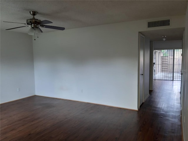 unfurnished room featuring a textured ceiling, dark wood-type flooring, visible vents, and a ceiling fan