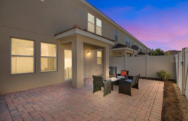 patio terrace at dusk featuring cooling unit and a fenced backyard