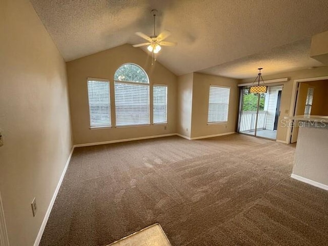 carpeted empty room featuring lofted ceiling, a textured ceiling, a ceiling fan, and baseboards