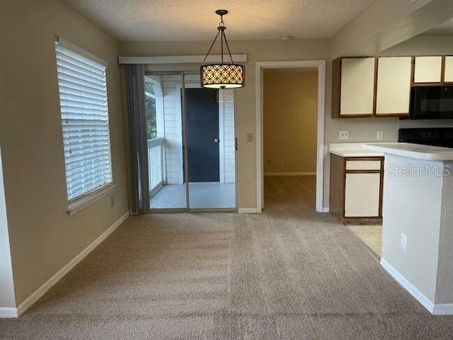 kitchen with light colored carpet, black microwave, white cabinets, and a textured ceiling