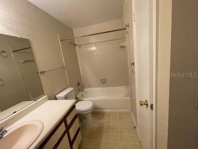 bathroom with shower / bath combination, a textured wall, vanity, and toilet