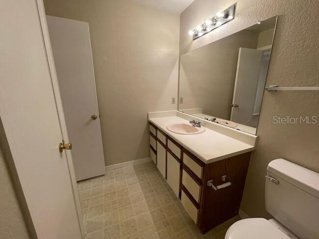 bathroom featuring a textured wall, vanity, and toilet