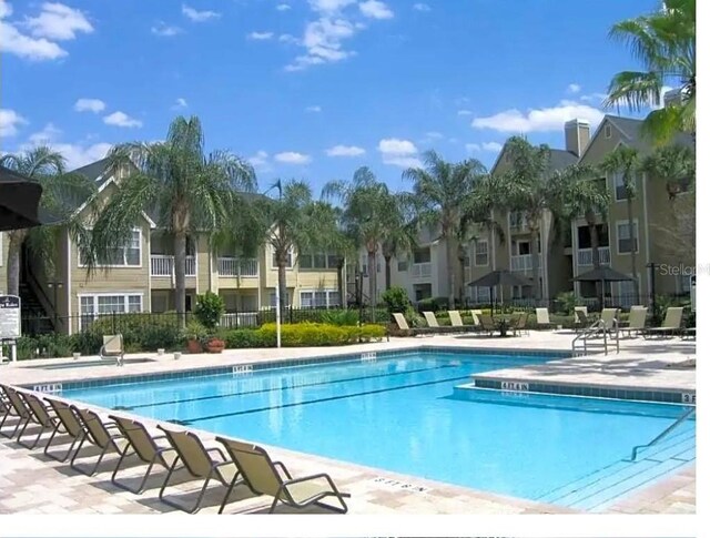 community pool with a patio and fence