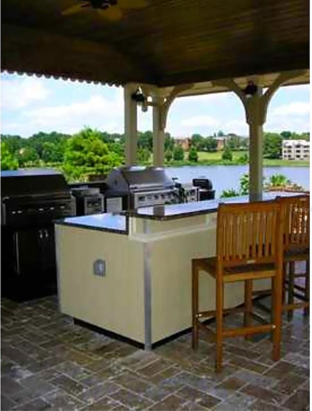 view of patio with a water view, exterior kitchen, and area for grilling