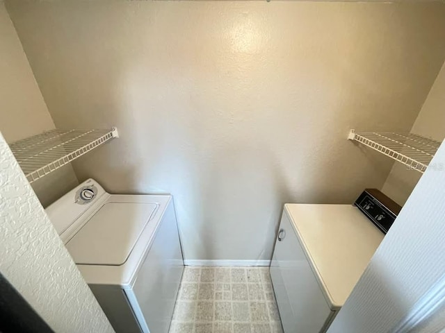 clothes washing area with laundry area, washing machine and clothes dryer, and baseboards