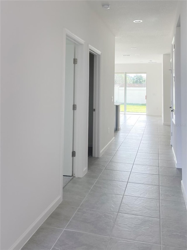 hallway featuring light tile patterned floors and baseboards