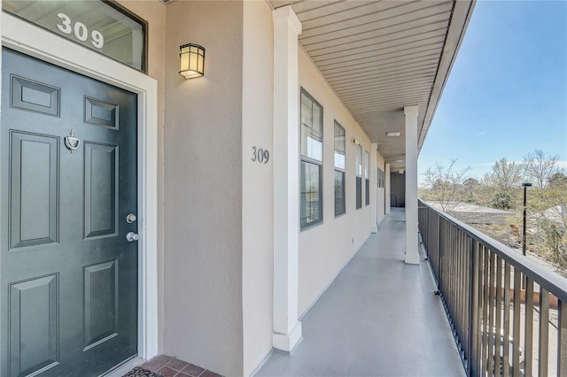 view of exterior entry with stucco siding and a balcony