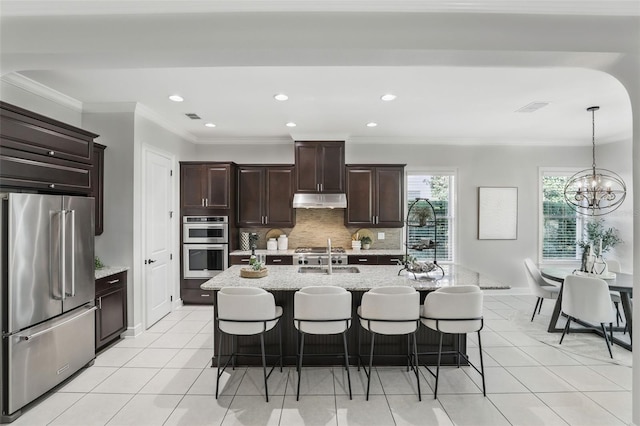 kitchen with stainless steel appliances, visible vents, decorative backsplash, under cabinet range hood, and a kitchen bar