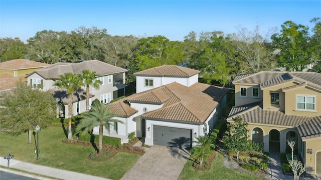 mediterranean / spanish-style home with decorative driveway, a tile roof, stucco siding, a garage, and a front lawn