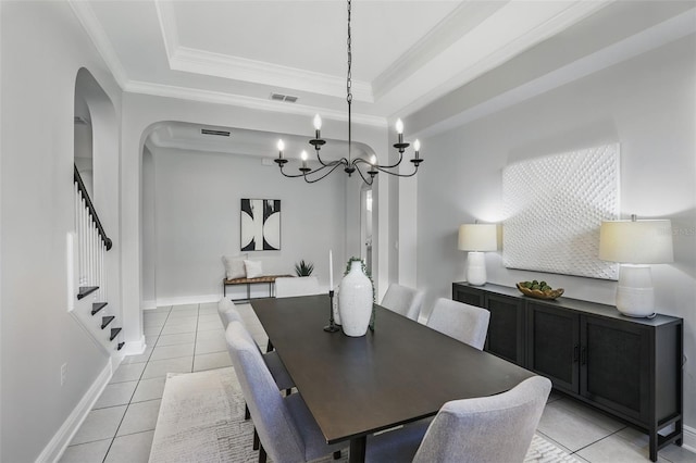 dining space featuring light tile patterned floors, arched walkways, ornamental molding, stairway, and a tray ceiling