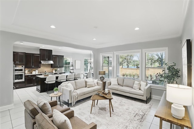 living room featuring light tile patterned floors, baseboards, and crown molding