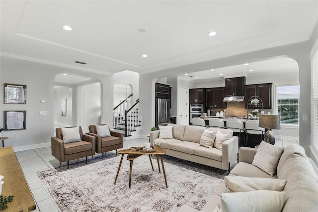 living area featuring arched walkways, stairs, visible vents, and crown molding