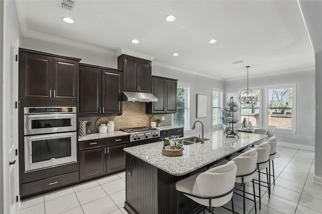 kitchen featuring stainless steel appliances, decorative backsplash, ornamental molding, a sink, and under cabinet range hood