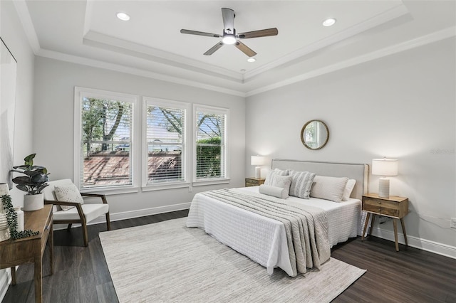 bedroom featuring ornamental molding, a tray ceiling, dark wood-style flooring, and baseboards