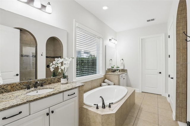 bathroom featuring tile patterned floors, two vanities, a sink, a tile shower, and a bath