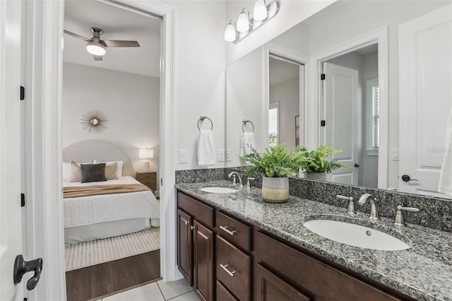 ensuite bathroom featuring ceiling fan, connected bathroom, a sink, and tile patterned floors