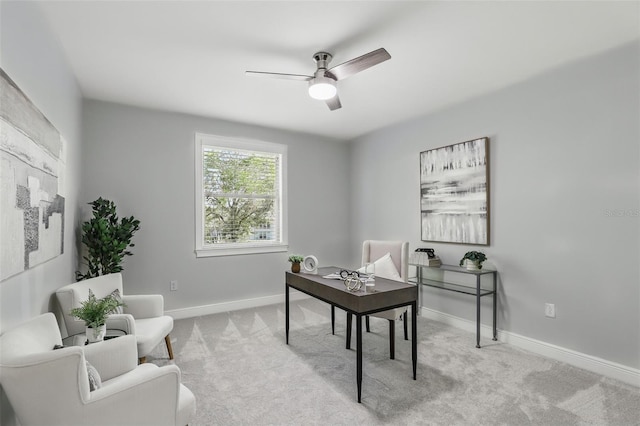 carpeted office space featuring ceiling fan and baseboards