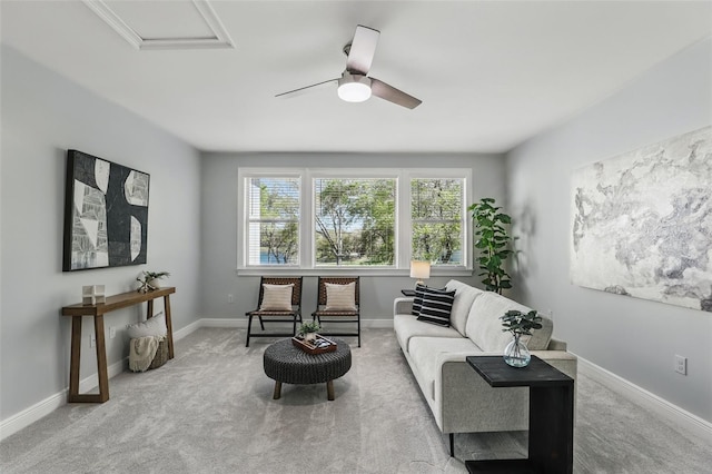 living area featuring carpet, baseboards, ceiling fan, and attic access