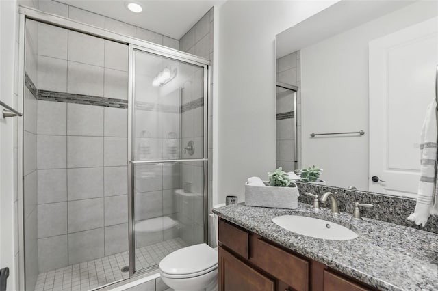 bathroom featuring vanity, a shower stall, and toilet