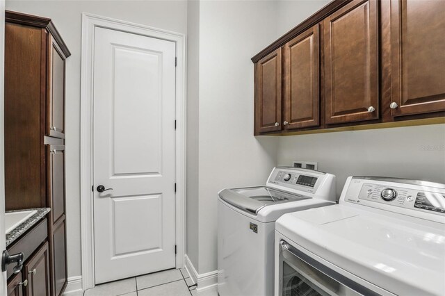 laundry room with light tile patterned floors, washing machine and dryer, cabinet space, and baseboards