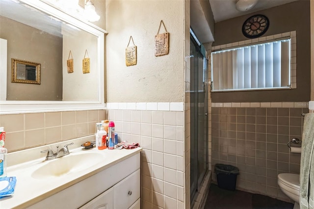 full bath featuring vanity, a stall shower, wainscoting, tile walls, and toilet