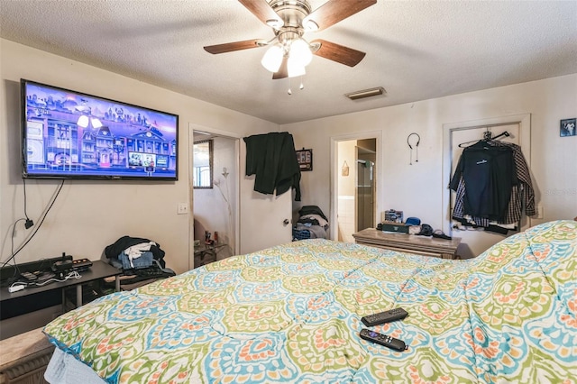 bedroom with visible vents, connected bathroom, a textured ceiling, and a ceiling fan