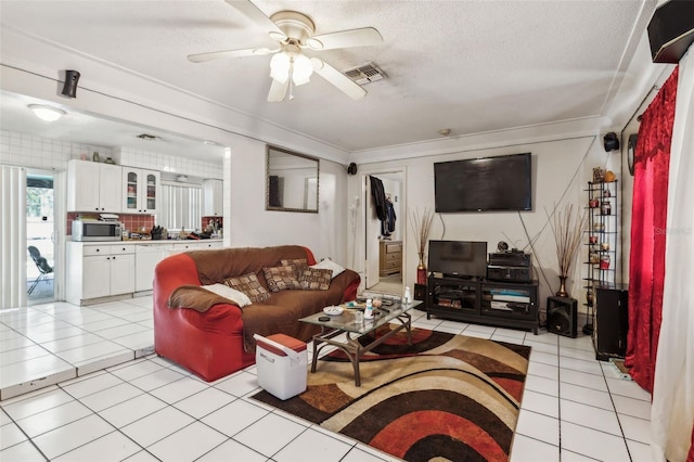 living area featuring visible vents, crown molding, light tile patterned flooring, a textured ceiling, and a ceiling fan