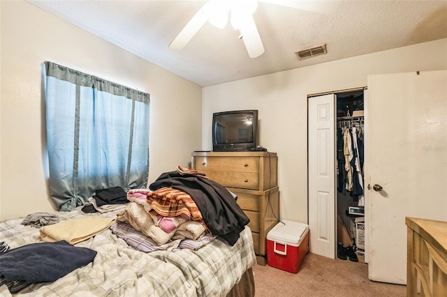 bedroom with visible vents, light carpet, a ceiling fan, a textured ceiling, and a closet