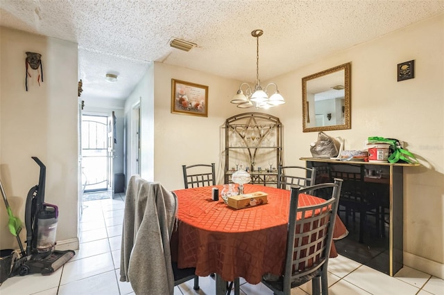 dining area with light tile patterned flooring, visible vents, a chandelier, and a textured ceiling