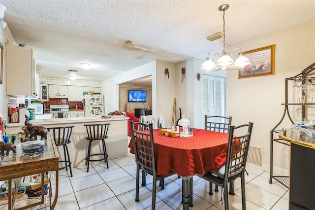 dining room featuring an inviting chandelier, light tile patterned floors, visible vents, and a textured ceiling