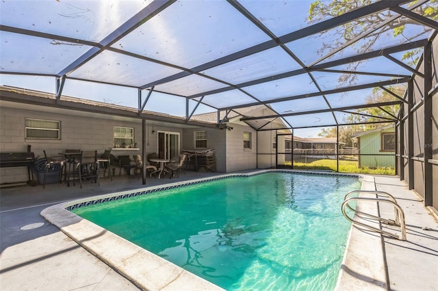 outdoor pool with glass enclosure, a patio, and area for grilling