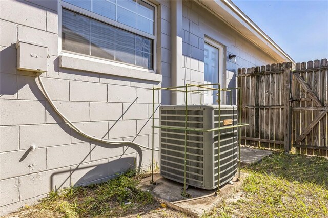 details with concrete block siding, a gate, central AC unit, and fence