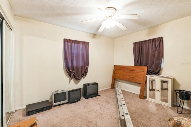 carpeted bedroom featuring baseboards, a closet, a textured ceiling, and ceiling fan