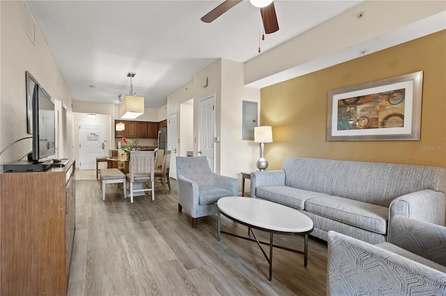 living area featuring light wood finished floors, ceiling fan, electric panel, and visible vents