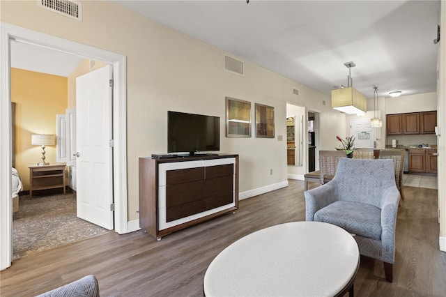 living room with wood finished floors, visible vents, and baseboards