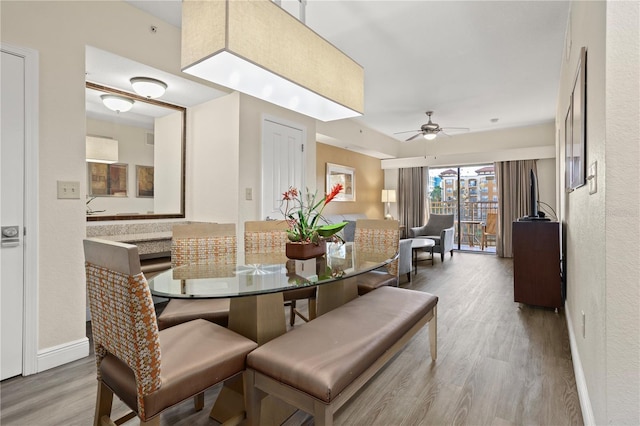 dining space featuring a ceiling fan, baseboards, and wood finished floors